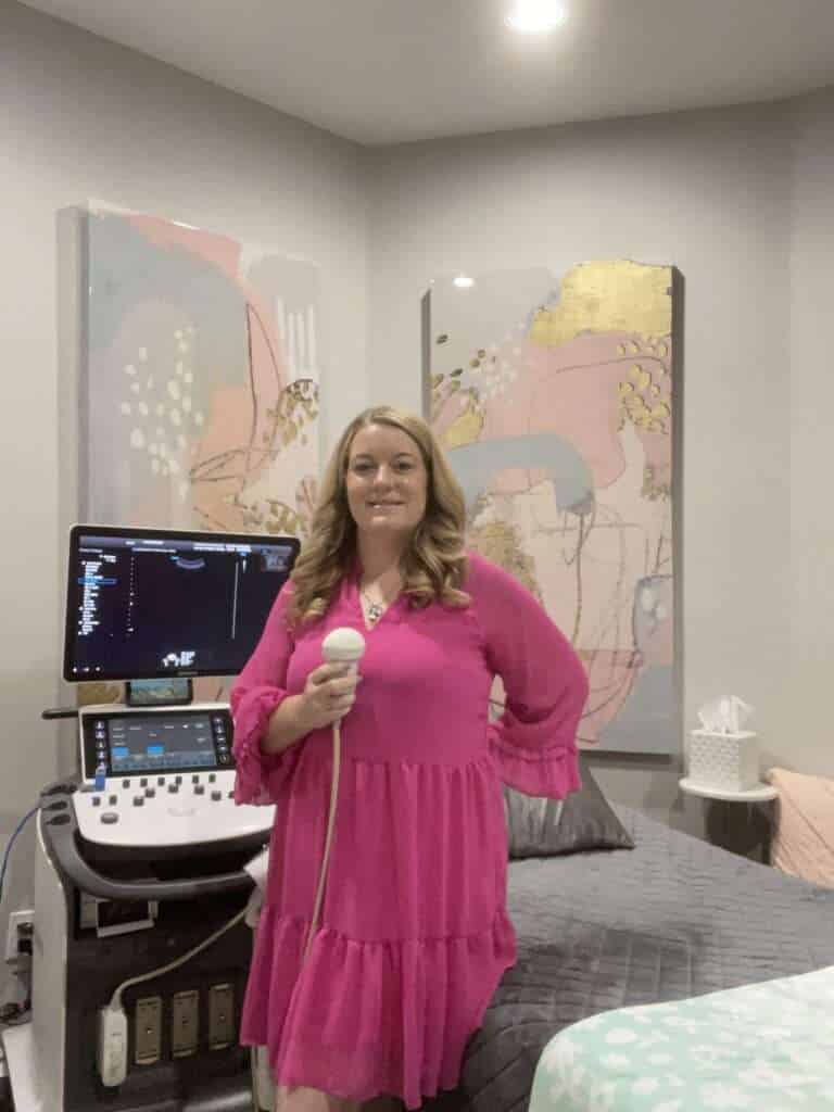 Stormy, owner of Peeping Moms holding a transducer next to an ultrasound machine